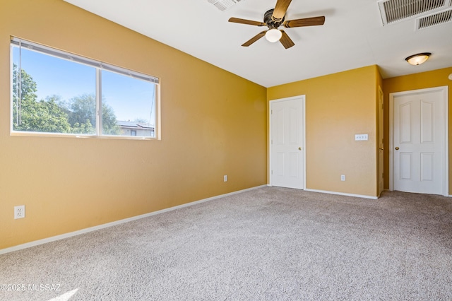 unfurnished room with carpet, visible vents, a ceiling fan, and baseboards