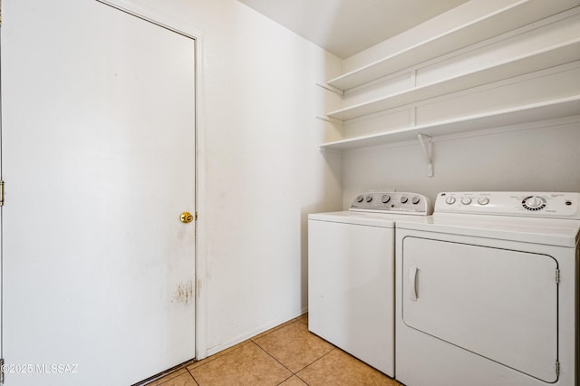 clothes washing area featuring light tile patterned flooring, independent washer and dryer, and laundry area