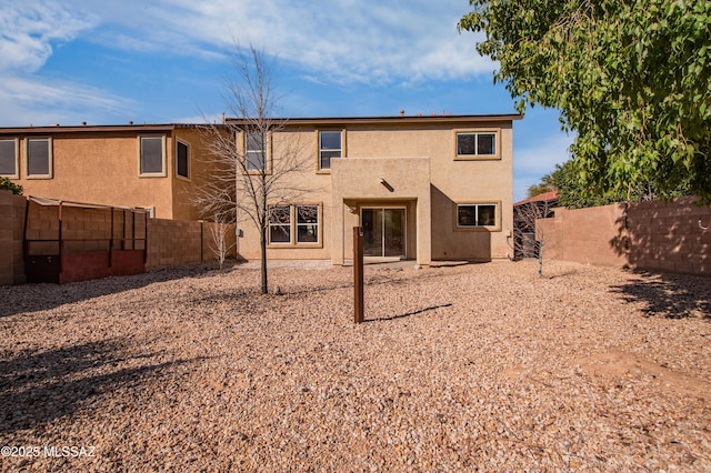 rear view of property featuring a fenced backyard and stucco siding