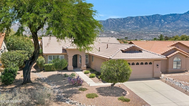 view of front facade with an attached garage, a mountain view, a tile roof, concrete driveway, and stucco siding