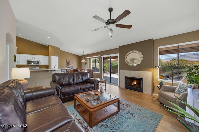 living room featuring lofted ceiling, recessed lighting, ceiling fan, light wood-style floors, and a fireplace
