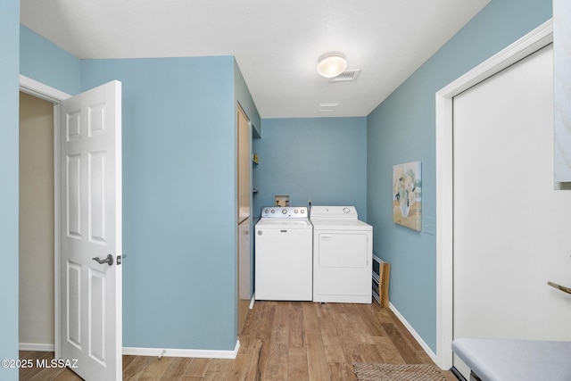 laundry area featuring washer and clothes dryer, laundry area, light wood-type flooring, visible vents, and baseboards
