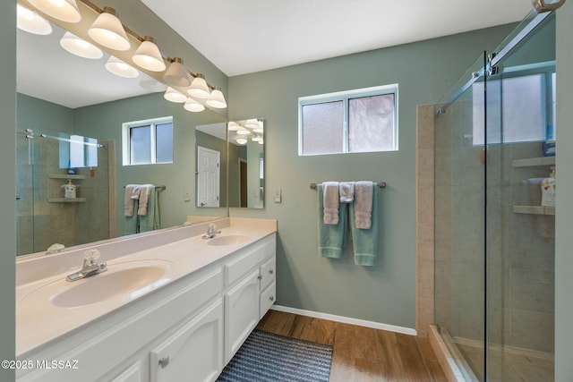full bathroom featuring a stall shower, double vanity, a sink, and wood finished floors