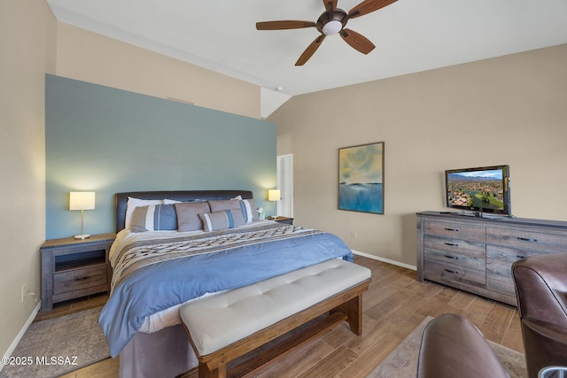 bedroom featuring lofted ceiling, baseboards, a ceiling fan, and wood finished floors