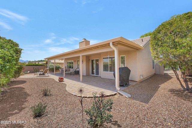 back of house featuring a chimney, a patio area, stucco siding, and fence