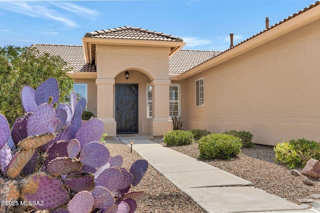 property entrance with a tiled roof and stucco siding
