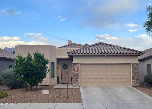 8898 N Treasure Mountain Dr, Tucson, AZ 85742 - view of front of house with stone siding, concrete driveway, a garage, and stucco siding