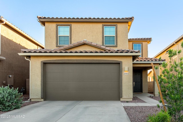 mediterranean / spanish home featuring driveway, a tiled roof, stucco siding, and an attached garage