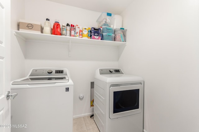 washroom featuring light tile patterned flooring, washing machine and clothes dryer, laundry area, and baseboards