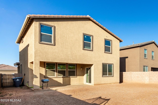 rear view of house with a patio, a gate, a fenced backyard, and stucco siding