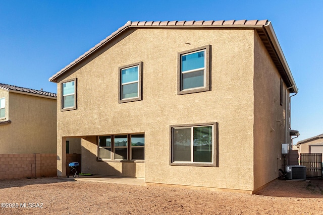 rear view of house featuring a patio area, central air condition unit, stucco siding, and fence
