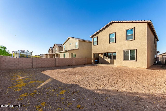 back of house featuring stucco siding, a fenced backyard, and central AC unit