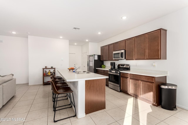 kitchen featuring a sink, a kitchen bar, visible vents, appliances with stainless steel finishes, and an island with sink
