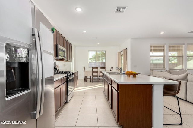 kitchen featuring a sink, stainless steel appliances, light tile patterned floors, visible vents, and open floor plan