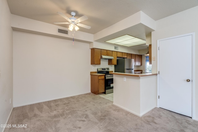 kitchen featuring under cabinet range hood, ceiling fan, brown cabinetry, light carpet, and appliances with stainless steel finishes