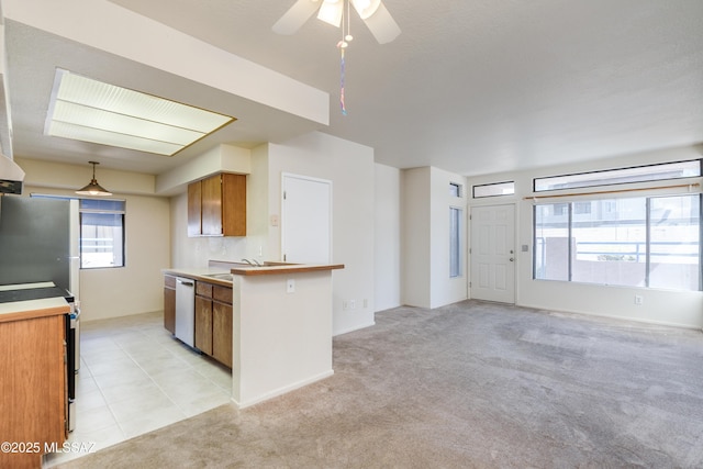 kitchen with light colored carpet, ceiling fan, stainless steel appliances, and brown cabinetry
