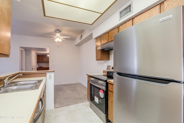 kitchen featuring a sink, under cabinet range hood, visible vents, appliances with stainless steel finishes, and light colored carpet