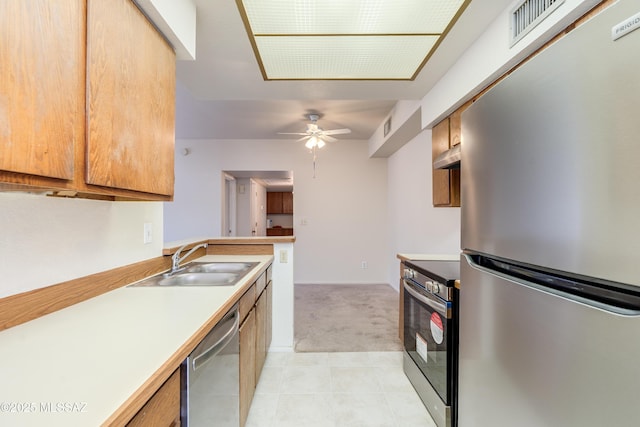 kitchen with stainless steel appliances, extractor fan, light countertops, light carpet, and a sink
