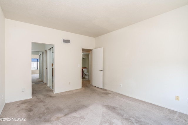carpeted spare room featuring baseboards and visible vents
