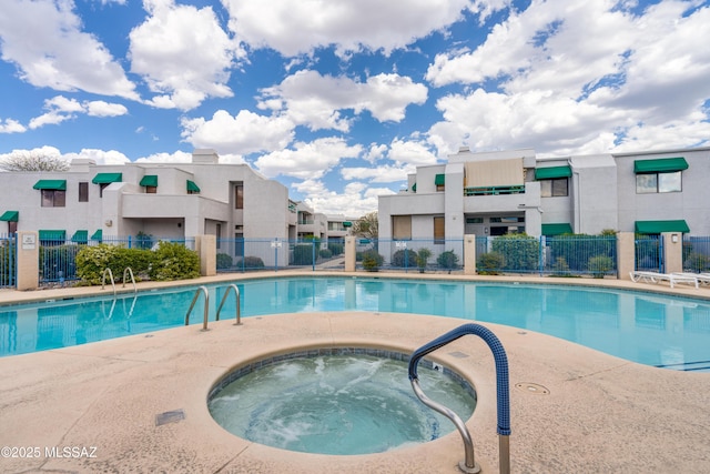 pool with fence, a community hot tub, and a residential view