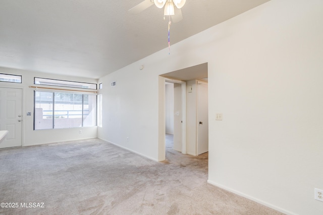 spare room featuring carpet, visible vents, a ceiling fan, and baseboards