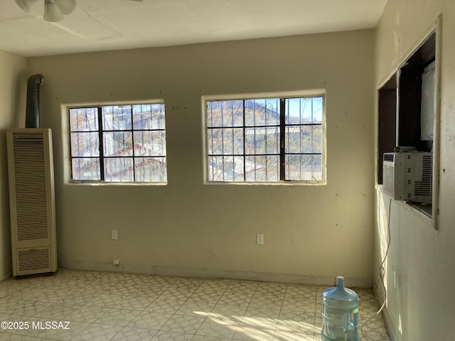interior space with ceiling fan, baseboards, a healthy amount of sunlight, and a heating unit
