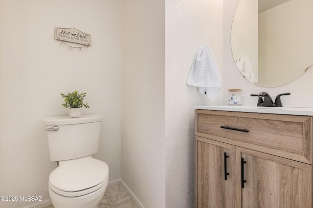 bathroom with toilet, baseboards, marble finish floor, and vanity