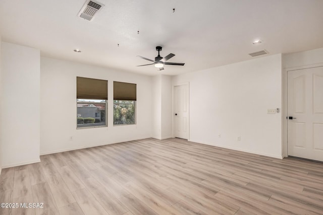 spare room featuring light wood finished floors, visible vents, baseboards, and ceiling fan