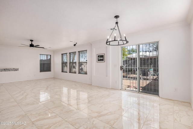 empty room with marble finish floor, ornamental molding, plenty of natural light, and ceiling fan with notable chandelier