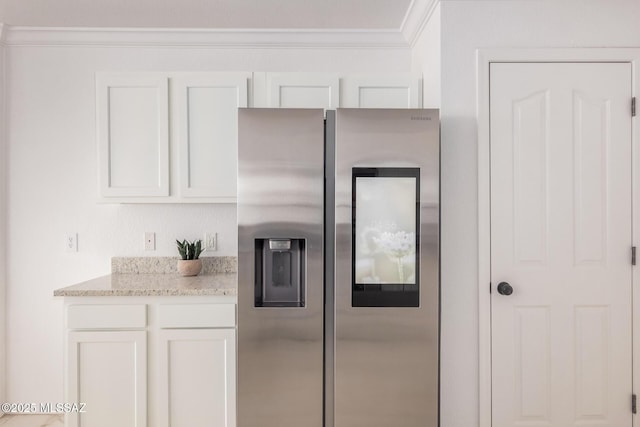kitchen featuring ornamental molding, light stone countertops, white cabinetry, and stainless steel fridge