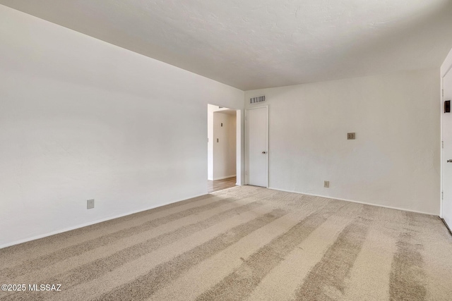 spare room with carpet floors, visible vents, and baseboards