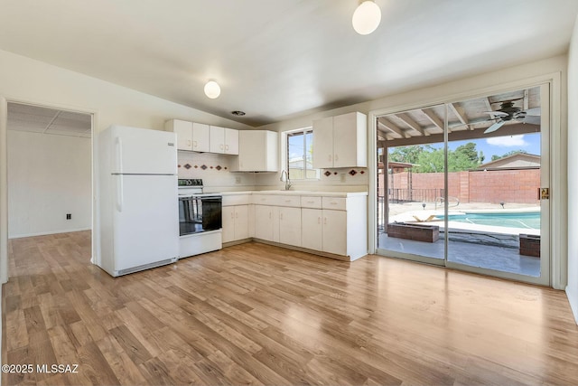 kitchen with a sink, freestanding refrigerator, light wood-style floors, range with electric stovetop, and light countertops