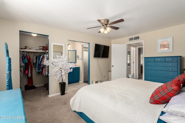 bedroom featuring visible vents, a closet, a walk in closet, light colored carpet, and connected bathroom
