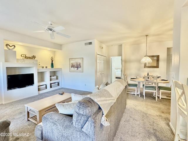 carpeted living area with baseboards, visible vents, and ceiling fan