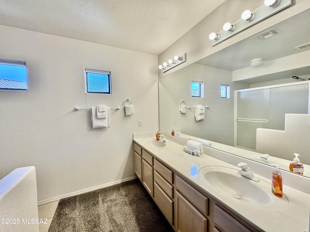 full bathroom with a shower with shower door, double vanity, visible vents, and a sink
