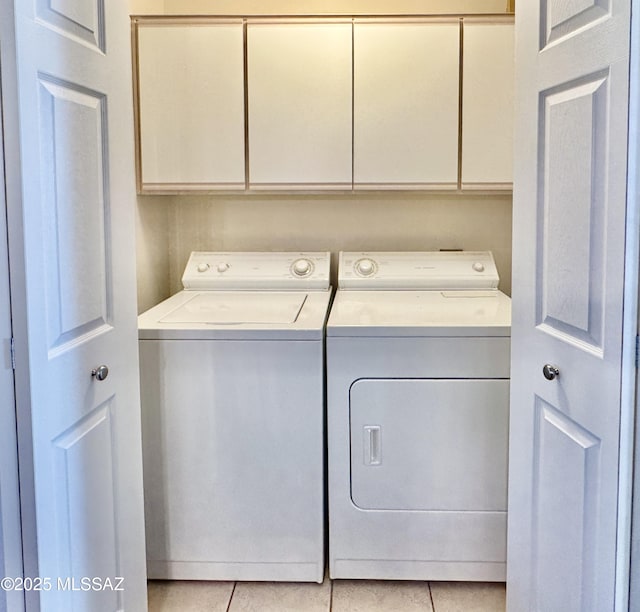 washroom with washing machine and clothes dryer, cabinet space, and light tile patterned floors