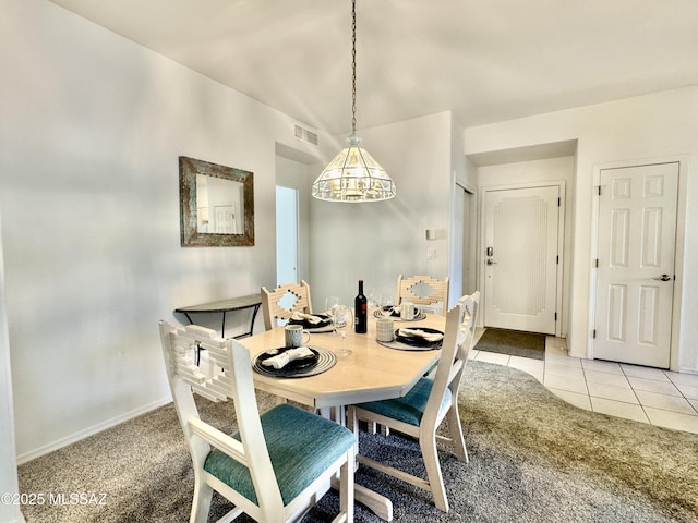 dining space with visible vents, light tile patterned floors, baseboards, a chandelier, and light colored carpet