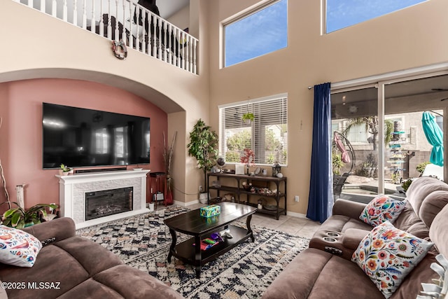 living area with baseboards, a wealth of natural light, tile patterned flooring, and a glass covered fireplace