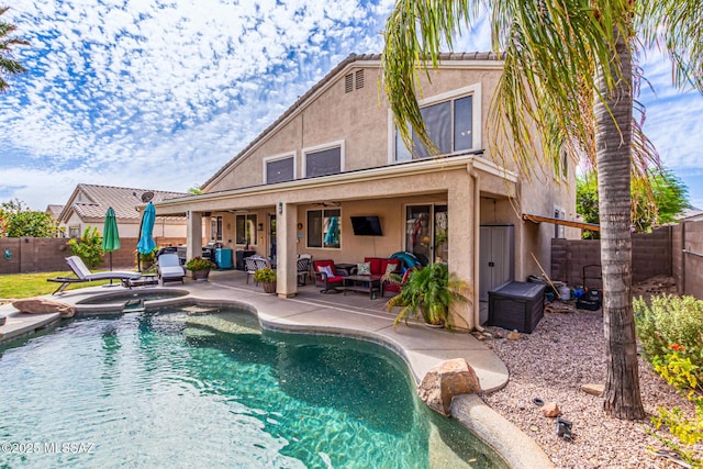 back of property featuring a patio, outdoor lounge area, stucco siding, a fenced backyard, and a pool with connected hot tub