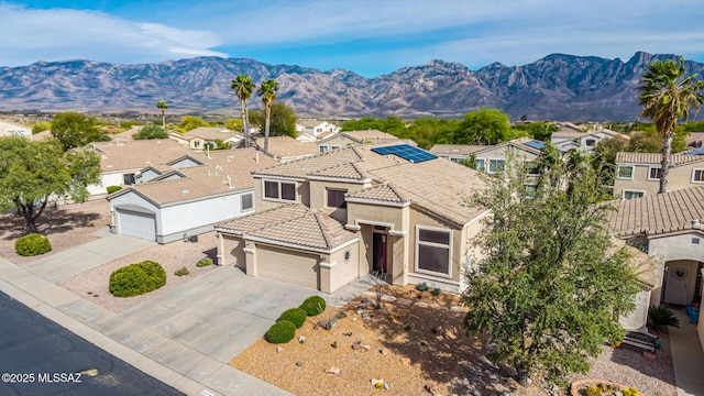 view of front of property with stucco siding, a tile roof, concrete driveway, and a residential view
