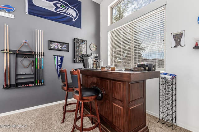bar with a bar, carpet, and baseboards