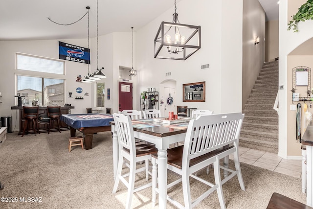dining space featuring high vaulted ceiling, arched walkways, stairs, and light colored carpet