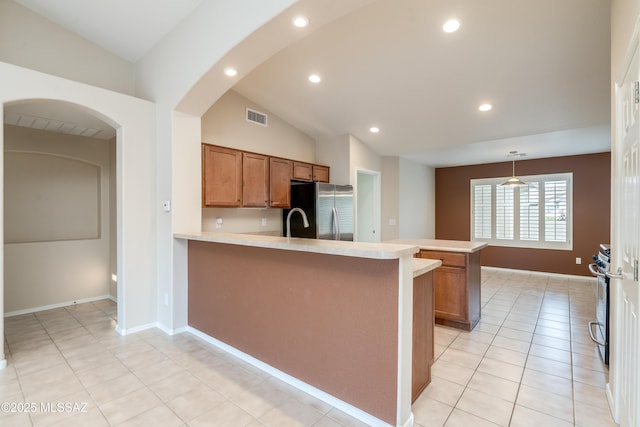 kitchen featuring stainless steel appliances, a peninsula, visible vents, and brown cabinetry