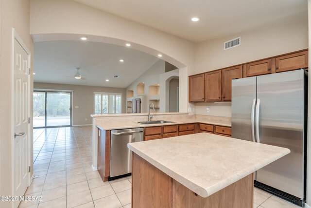 kitchen featuring stainless steel appliances, light countertops, visible vents, a sink, and brown cabinetry