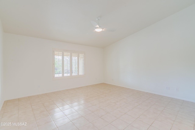 empty room with a ceiling fan, baseboards, vaulted ceiling, and light tile patterned floors