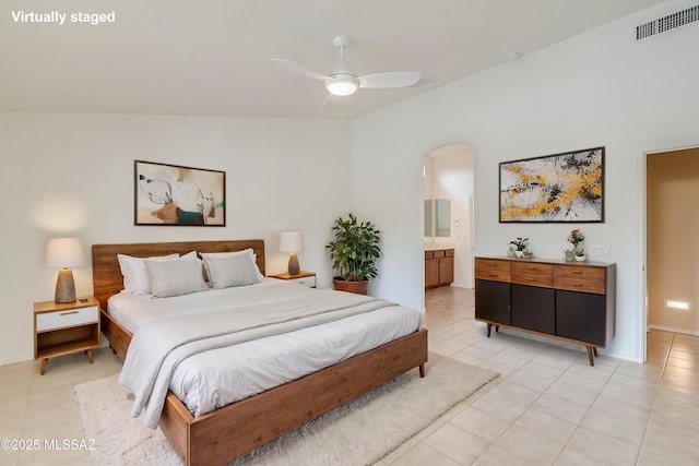 bedroom with arched walkways, visible vents, ensuite bath, and light tile patterned floors