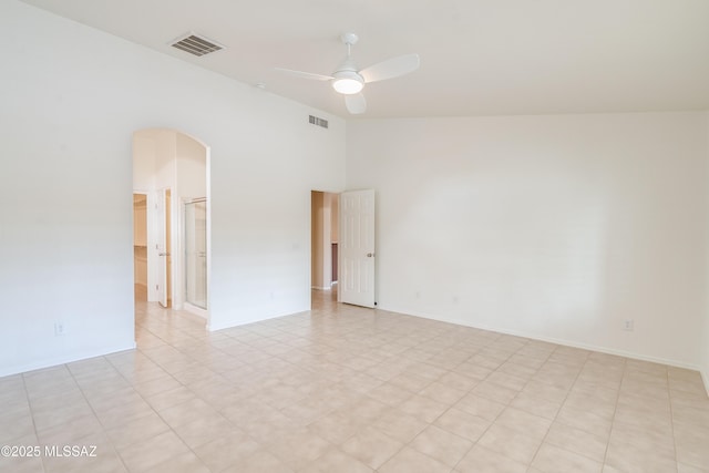 unfurnished room with arched walkways, visible vents, a ceiling fan, and baseboards