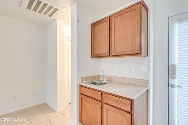 kitchen with a sink, light tile patterned flooring, baseboards, visible vents, and light countertops