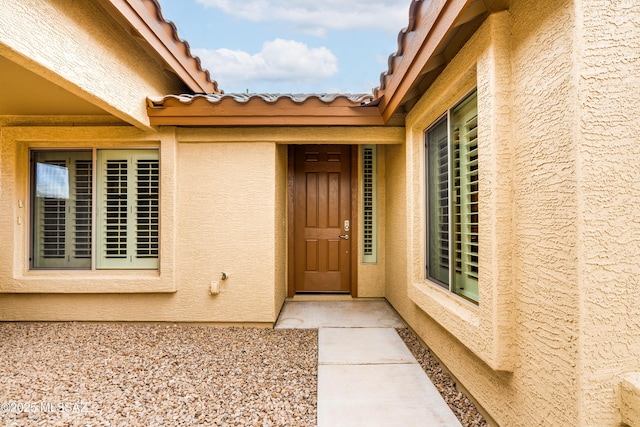 doorway to property with stucco siding and a tiled roof