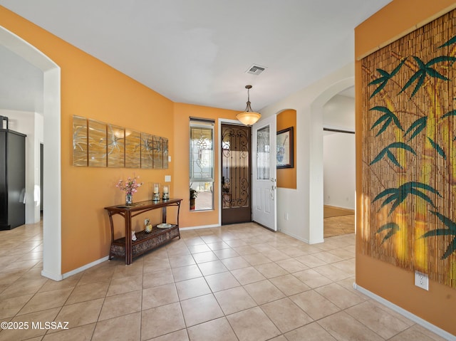 entryway featuring light tile patterned floors, arched walkways, and visible vents